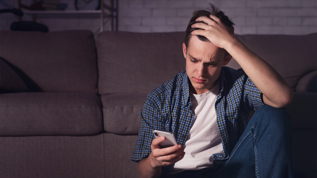 Adolescente stressato che usa lo smartphone, esempio di doomscrolling e calo dell'attenzione.